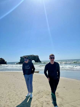 Michael Zhao and friend walking on beach by the Golden Gate Bridge