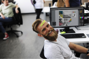 Photo of a man laughing in front of a computer