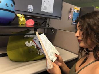 Co-worker reading a book in her cubicle at work