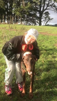 Lucy Zhang hugging a dog on a grassy field