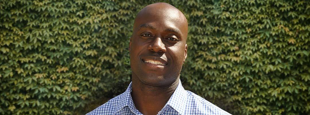 Project Management certificate graduate Toby Atawo outside in front of an ivy wall. Photo.