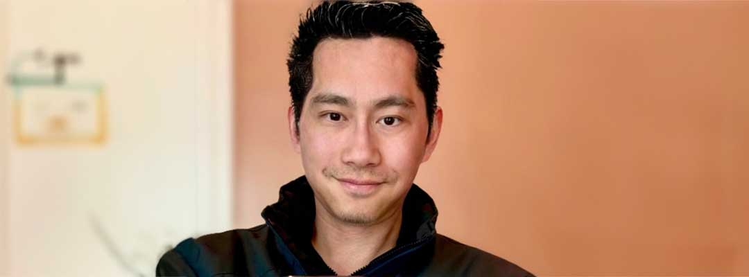 Photo of Benny Huang standing in front of orange wall