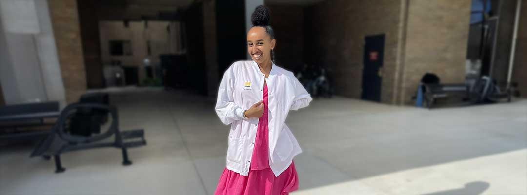 Brhan Eskinder wearing her white coat in front of a school building