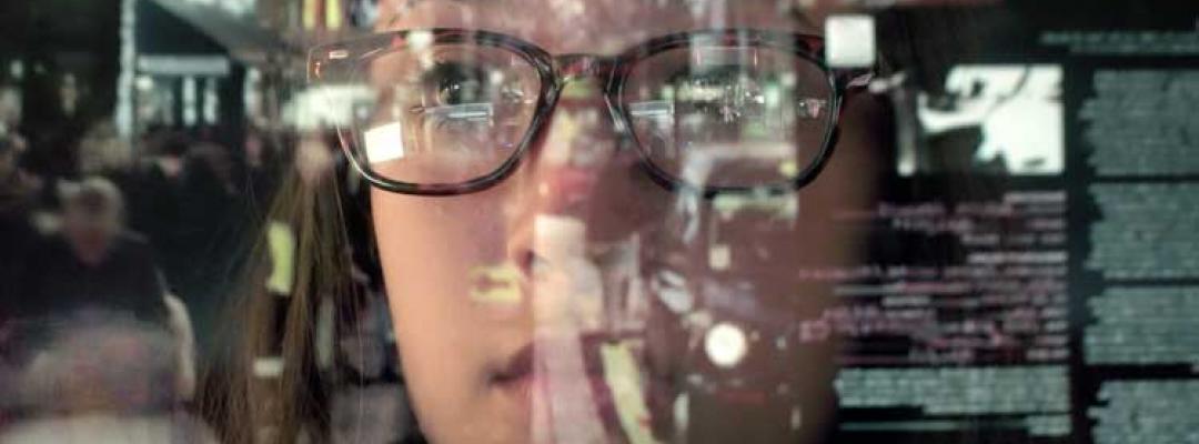 Data analyst gazing at glass wall covered in reflected data