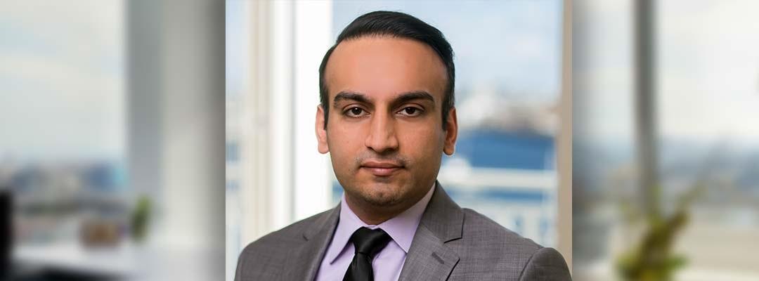 Headshot of Personal Financial Planning graduate Sandeep Gandhi wearing a gray suit, standing in front of a window. Photo.