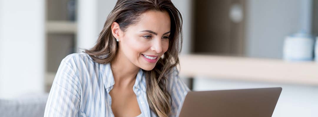 Woman in blue striped shirt viewing laptop