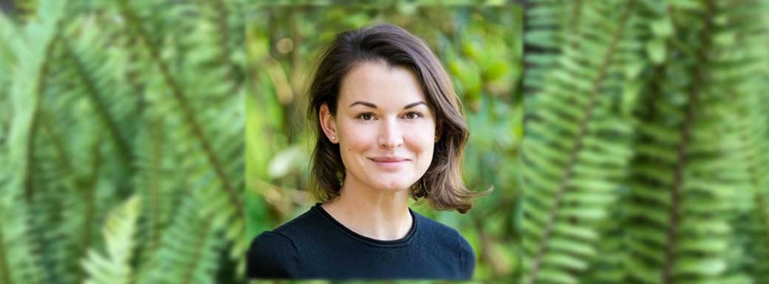 Headshot of Kseniya Norkina in front of foliage background