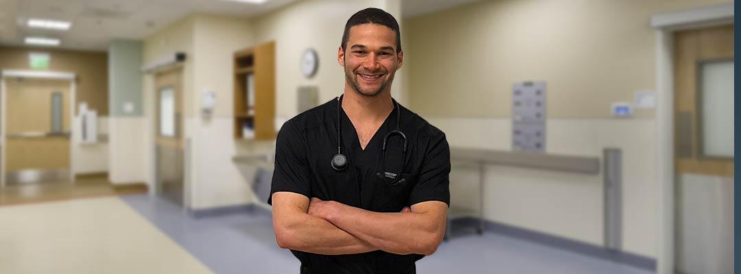 Alexander Lipson in his nursing outfit standing in front of a clinical setting