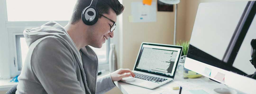 Student studying on a desk in front of a laptop and wearing headphones