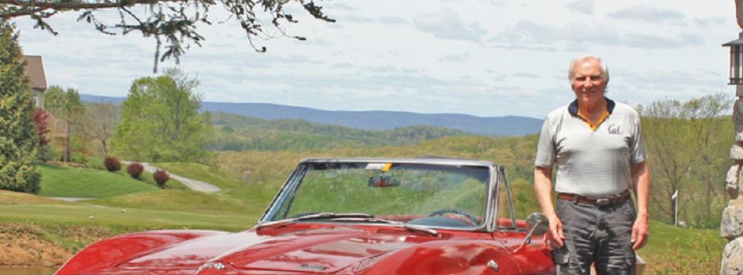 Writing certificate graduate and author Bill Truran next to a red sports car with hills behind him. Photo.