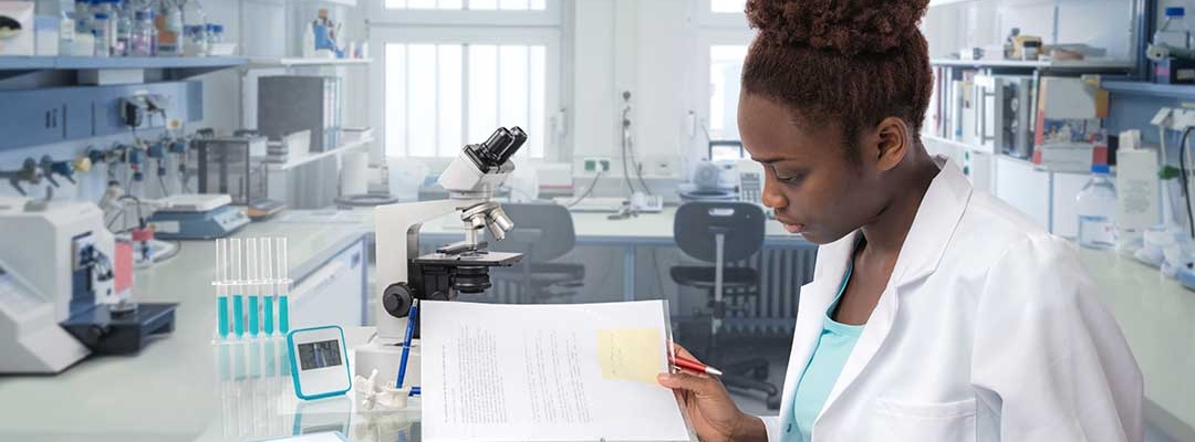 Black young female professional reading a manual in a science lab