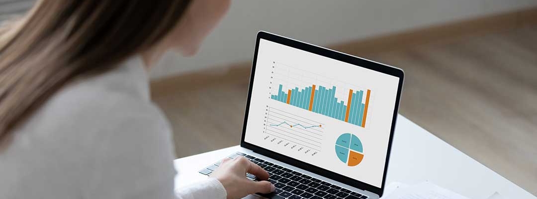 Woman working on laptop displaying business graphs