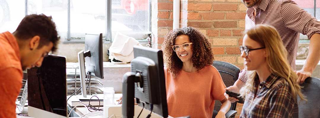 Group of young diverse tech professionals working at computers