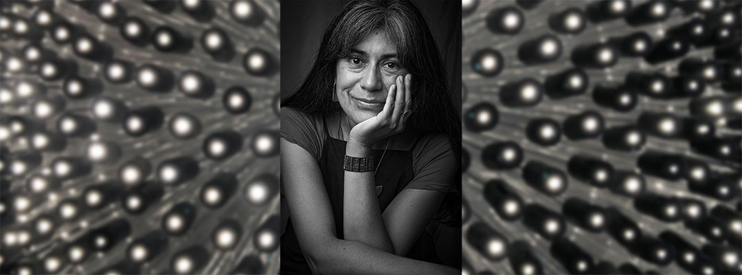 Headshot of Claudia Huenchuleo Paquien with artwork behind