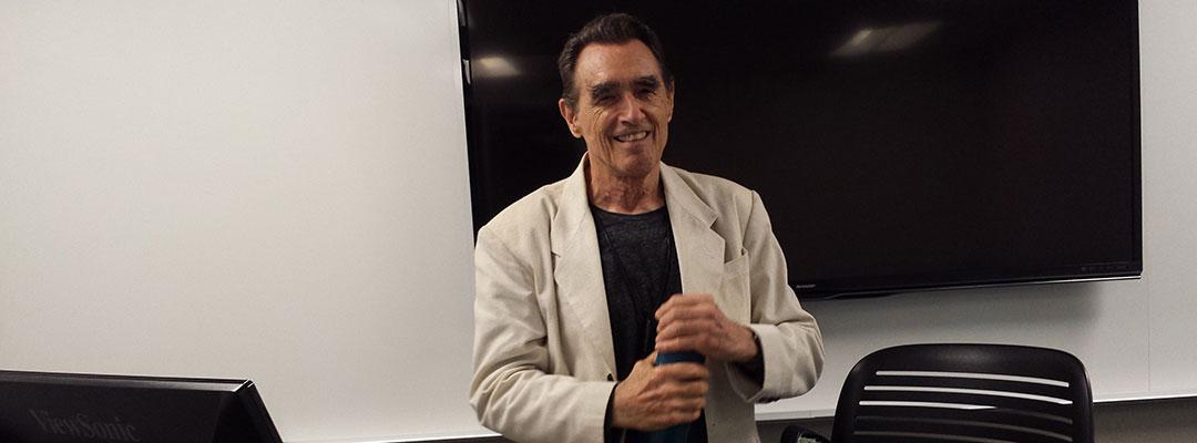 Writing instructor and poet Clive Matson standing in the front of a classroom at UC Berkeley Extension in San Francisco