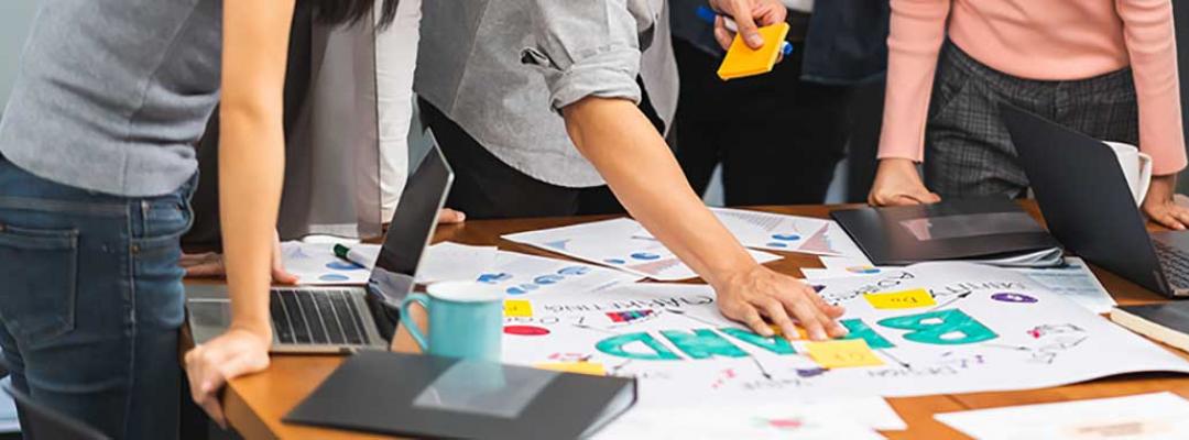 Photo of group of marketing professionals working on branding documents and sticky notes