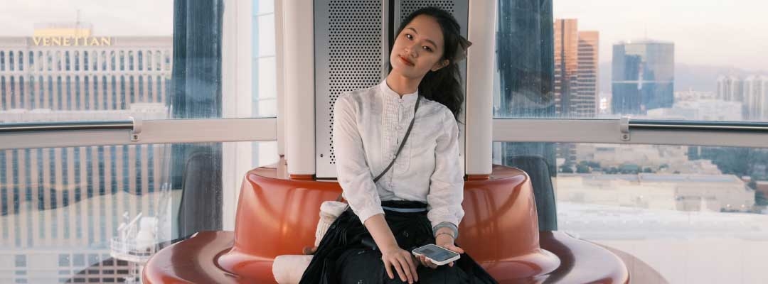 Lydia Bao sitting on an orange round couch in front of windows