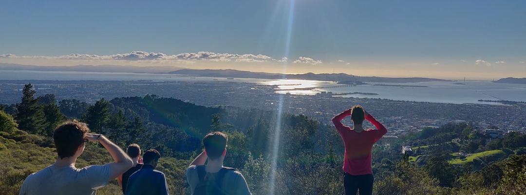 BHGAP student Markus and a few friends looking at a beautiful view of mountains and the ocean during a hike