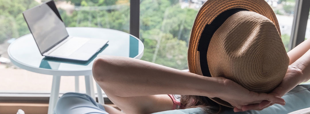 Stock photo of a woman with arms crossed behind her head in relaxation after working on her novel on a laptop.