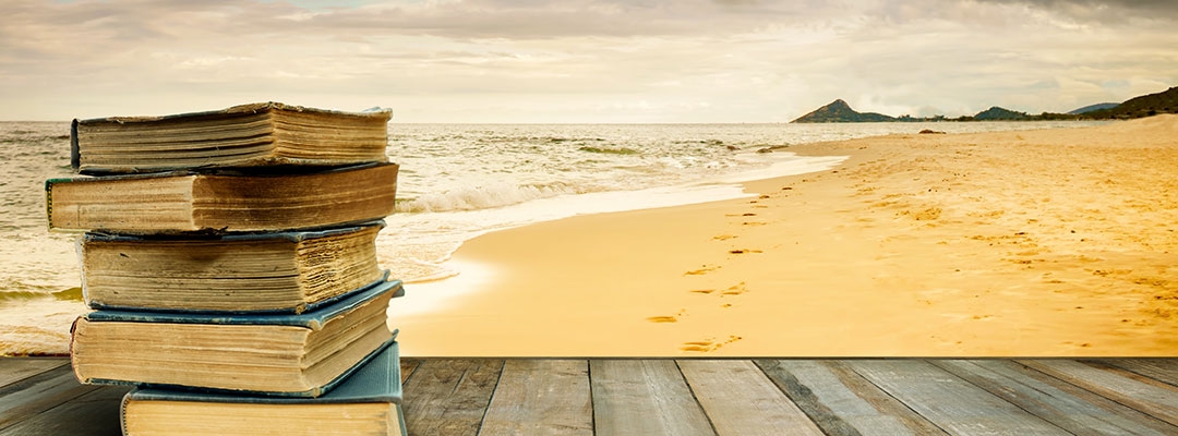 stock photo of a stack of books on a woden table by the beach