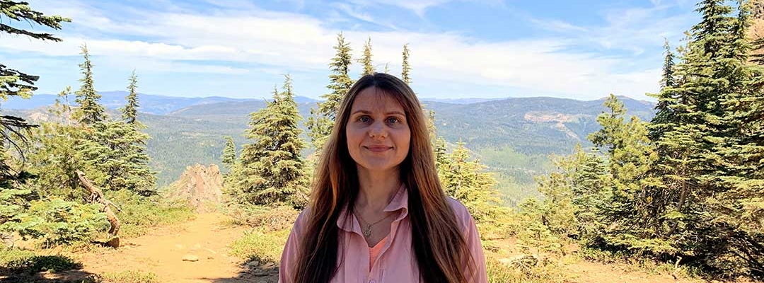 Photo of Tetiana Pairman in front of a forest and mountain background