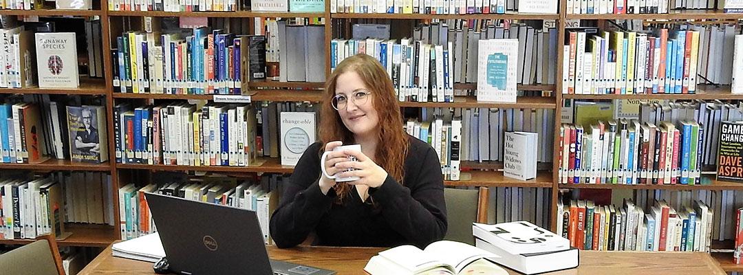 Editing student, scholarship winner Tracy Locken at a table in the library, with a laptop and books