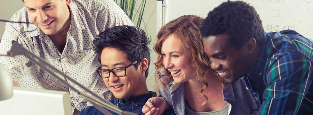 Photo of four diverse young professionals looking at a computer screen