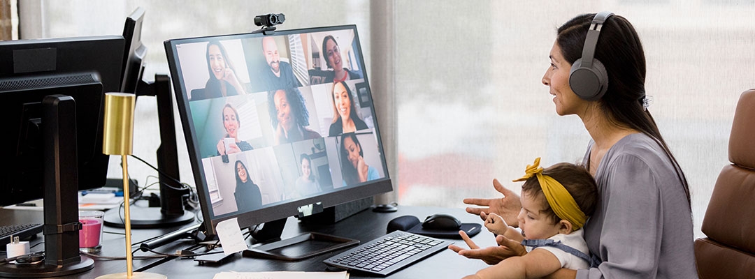 Woman with baby on lap on a departmental teleconference call at home