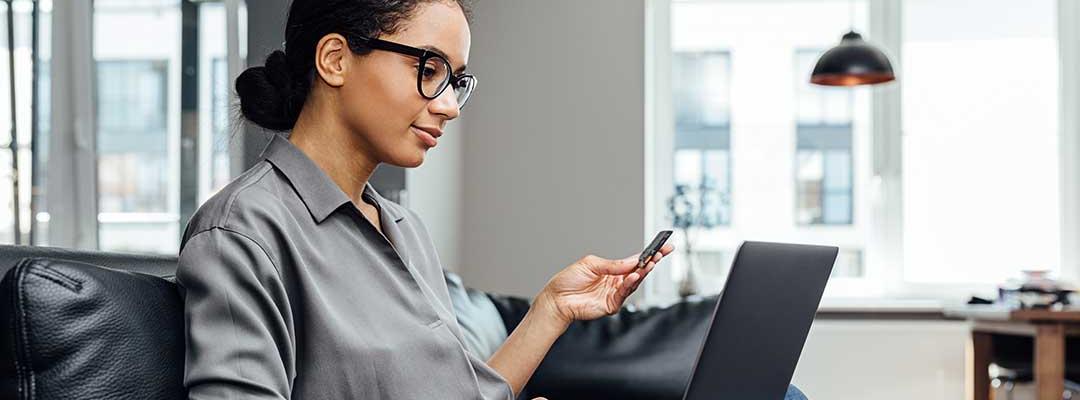 Photo of woman sitting on couch while working on a laptop