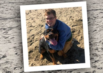 Post-Bacc Health Professions student, scholarship winner Matt Klinkel on a beach with a dog