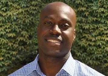 Project Management certificate graduate Toby Atawo outside in front of an ivy wall. Photo.