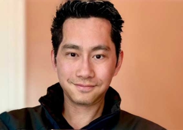 Photo of Benny Huang standing in front of orange wall