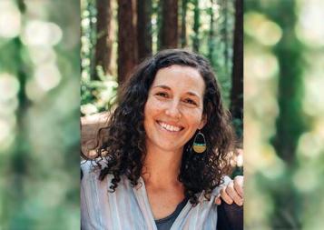 Photo of ESL Teacher Dana Neufeld in the forest wearing a rainbow shirt