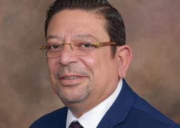 Headshot of UC Berkeley Extension accounting instructor Dr. Ehab Saad wearing a dark bue suit with brown background