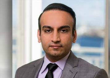 Headshot of Personal Financial Planning graduate Sandeep Gandhi wearing a gray suit, standing in front of a window. Photo.