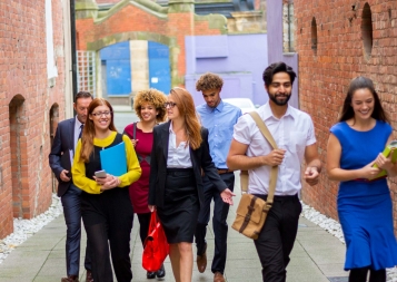 A group of seven young professionals and students walks down the street