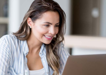 Woman in blue striped shirt viewing laptop