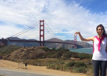 Graduate Maria Paula poses playfully in front of the Golden Gate bridge