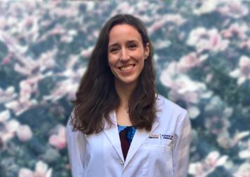 Photo of Laura Potter wearing white medical jacket in front of flower background