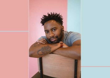 Photo of Reiss Reid sitting on a chair backward in front of a pink and blue background