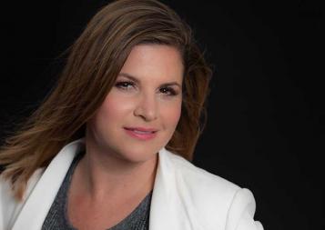 Instructor Renae Valdes wearing a white jacket in front of a black background