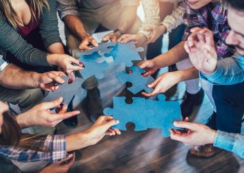 Photo of people holding blue pieces of a puzzle