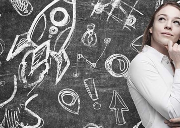 Business icons on blackboard with white young female professional standing in front