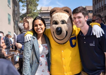 Two Berkeley students posing with Oski Bear in front of the camera