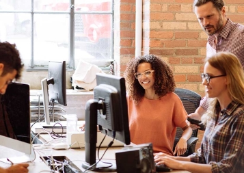 Group of young diverse tech professionals working at computers