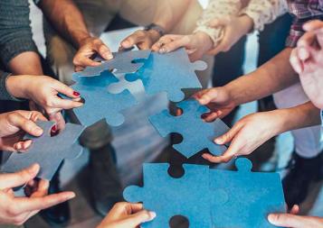 Photo of hands holding pieces of a jigsaw puzzle