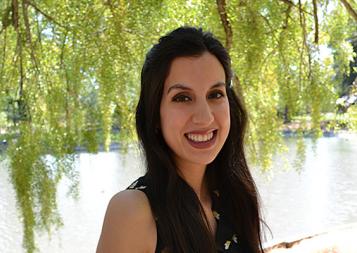 CLS Prep Program graduate Ester Fernandez standing by water, under a tree