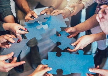 Multicultural employees putting together oversized jigsaw puzzle pieces