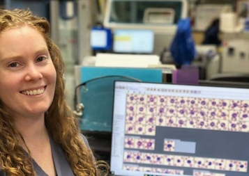 Photo of Gina LaMothe in the lab working on a laptop looking at blood samples