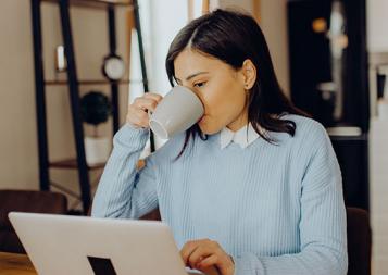 Stock photo of woman working from home and drinking coffee